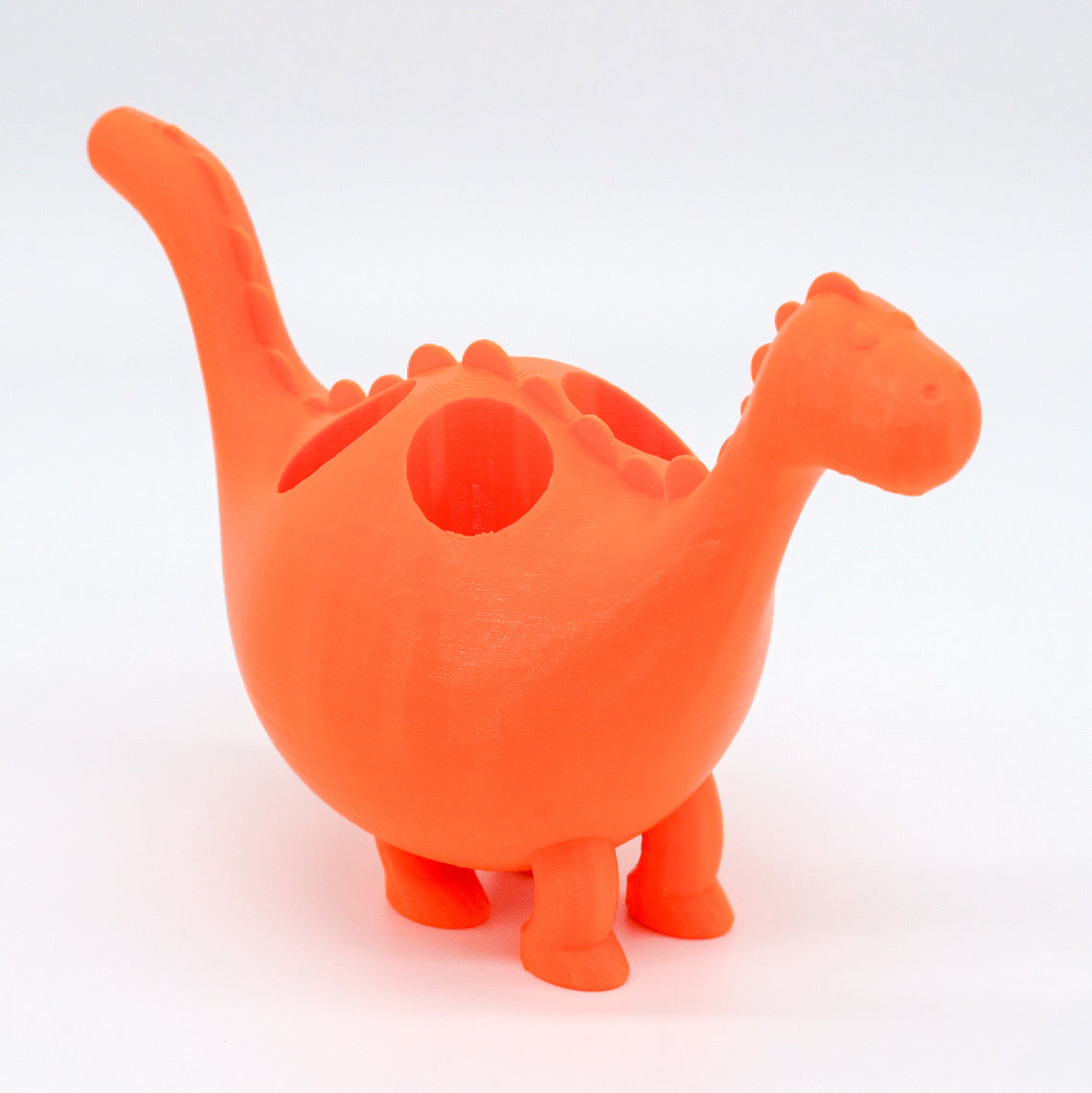 Présentoir en forme de dinosaure orange, imprimé en 3D, parfait pour exposer vos bouteilles d'huiles essentielles de 10 ml, apportant une note vive et joyeuse à votre décoration, disponible chez Essanzia.