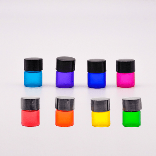 Ensemble de quatre bouteilles d'échantillonnage de 1 ml en verre coloré, chacune avec un capuchon noir, idéales pour partager des huiles essentielles ou des parfums.