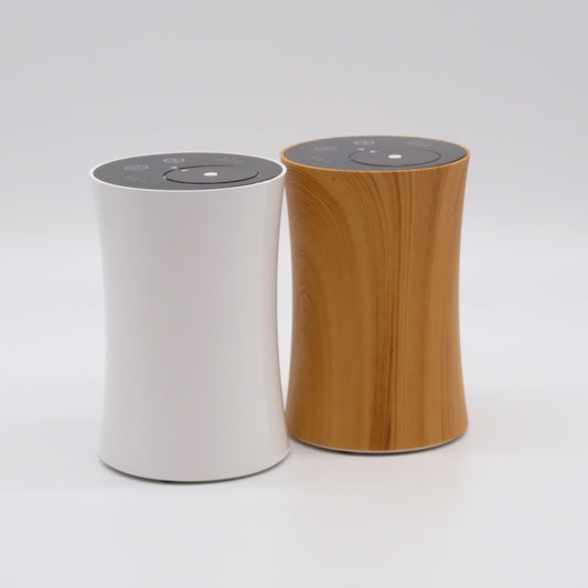 Deux diffuseurs d’huiles essentielles, finis blanc et bois, design courbé avec commandes tactiles sur le dessus.