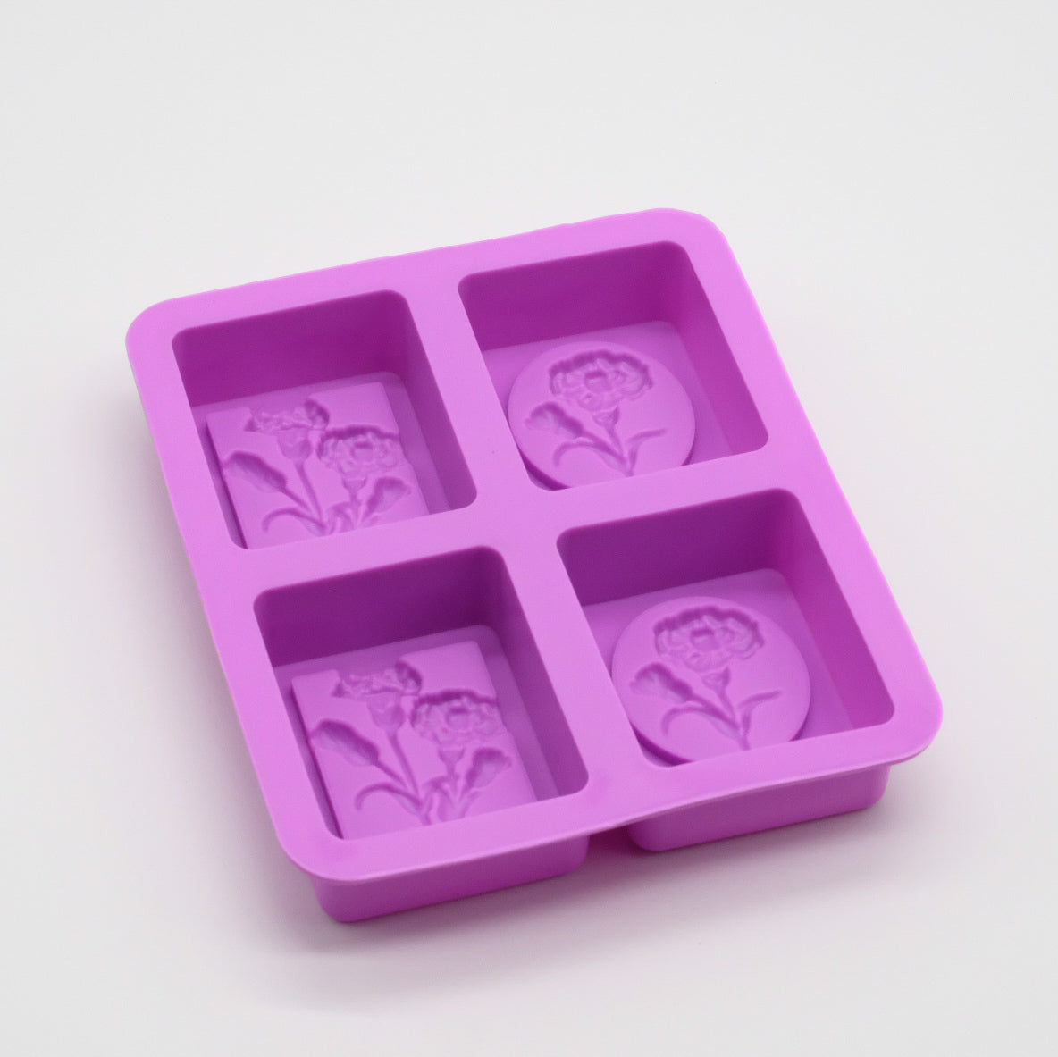 Moule en silicone violet avec 4 empreintes carrées, motif de fleur en relief; idéal pour savons ou barres solides.