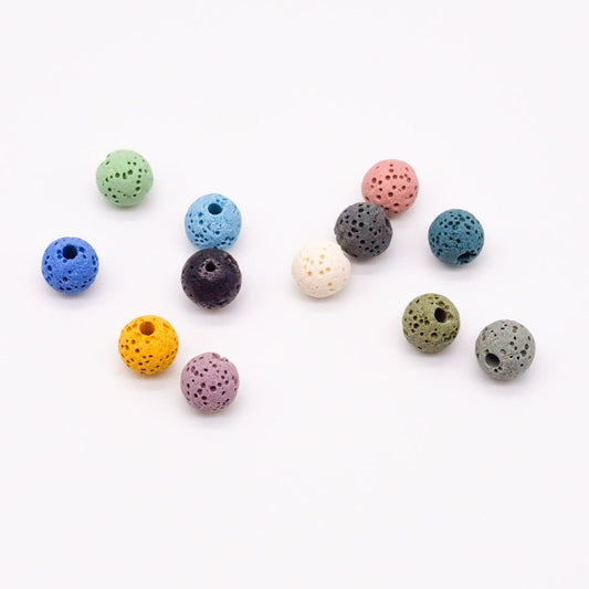 Ensemble de pierres de lave colorées en 11 teintes différentes, conçues pour être utilisées comme accessoires dans les colliers diffuseurs d'huiles essentielles, disponibles chez Essanzia.